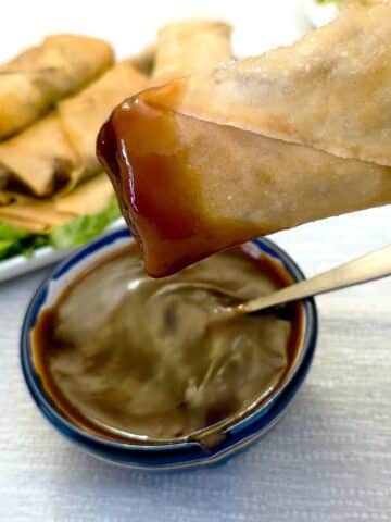 A crispy prawn spring roll that has been dipped in dipping sauce.