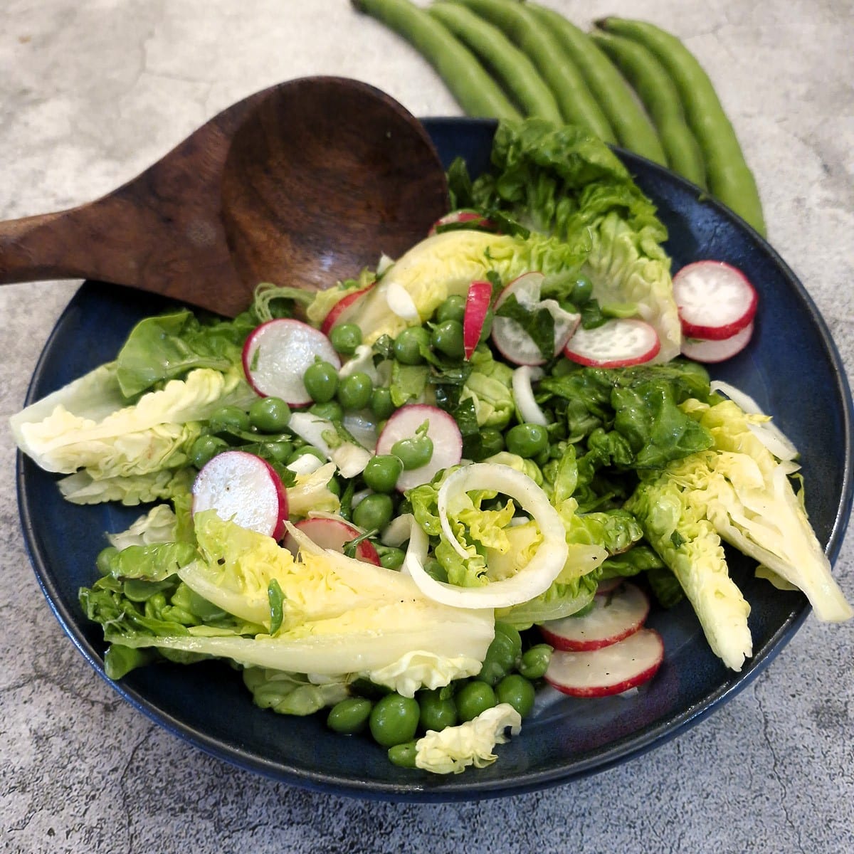 A dish of fresh pea and bean salad on a table.