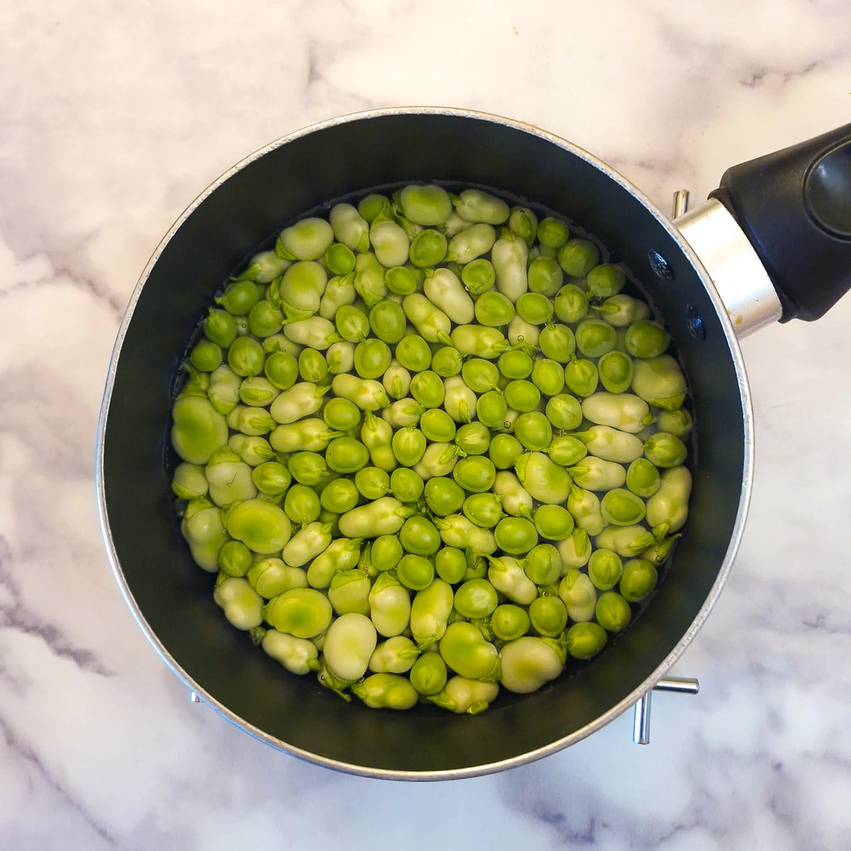 Peas and broad beans in a small saucepan.