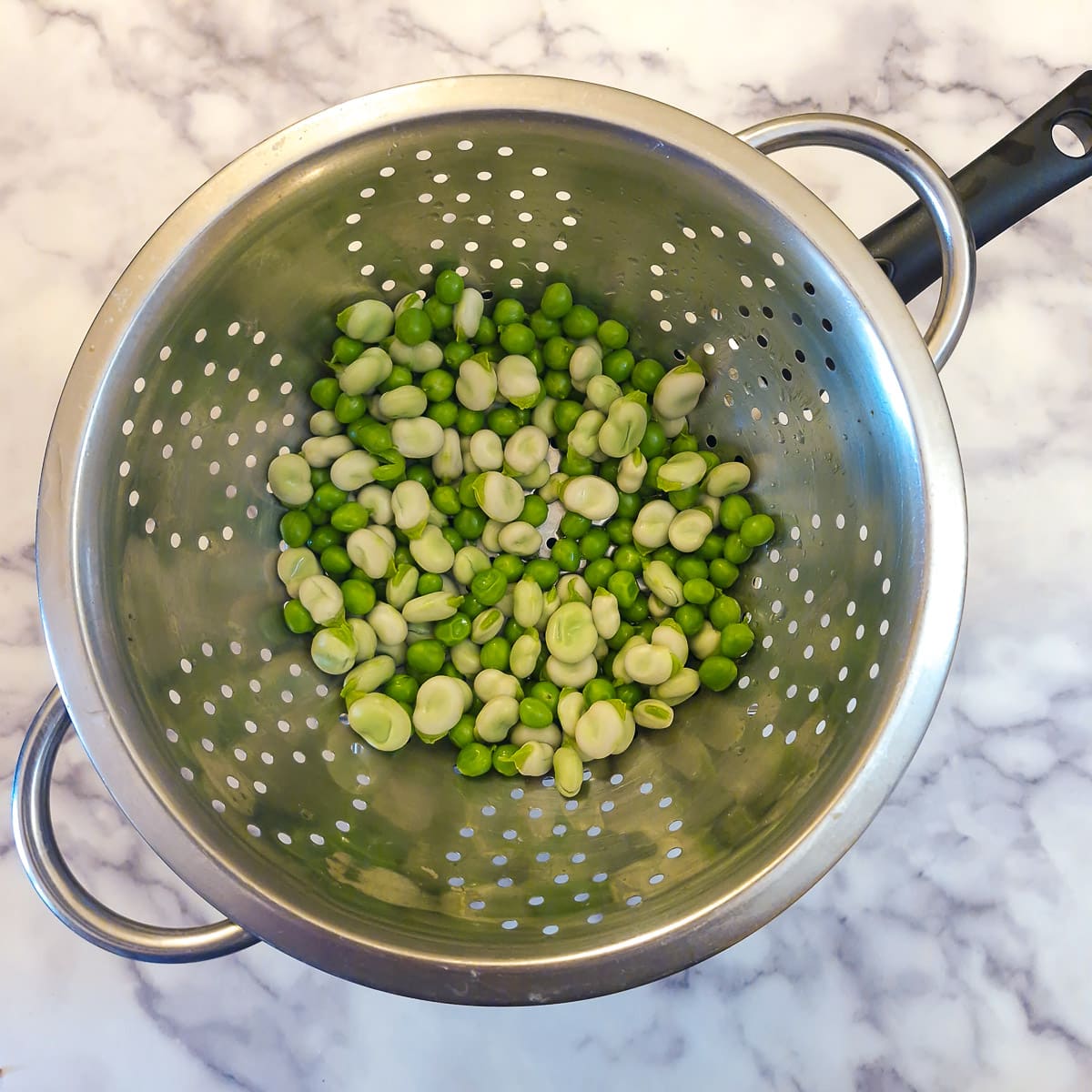 Peas and beans draining in a colander.
