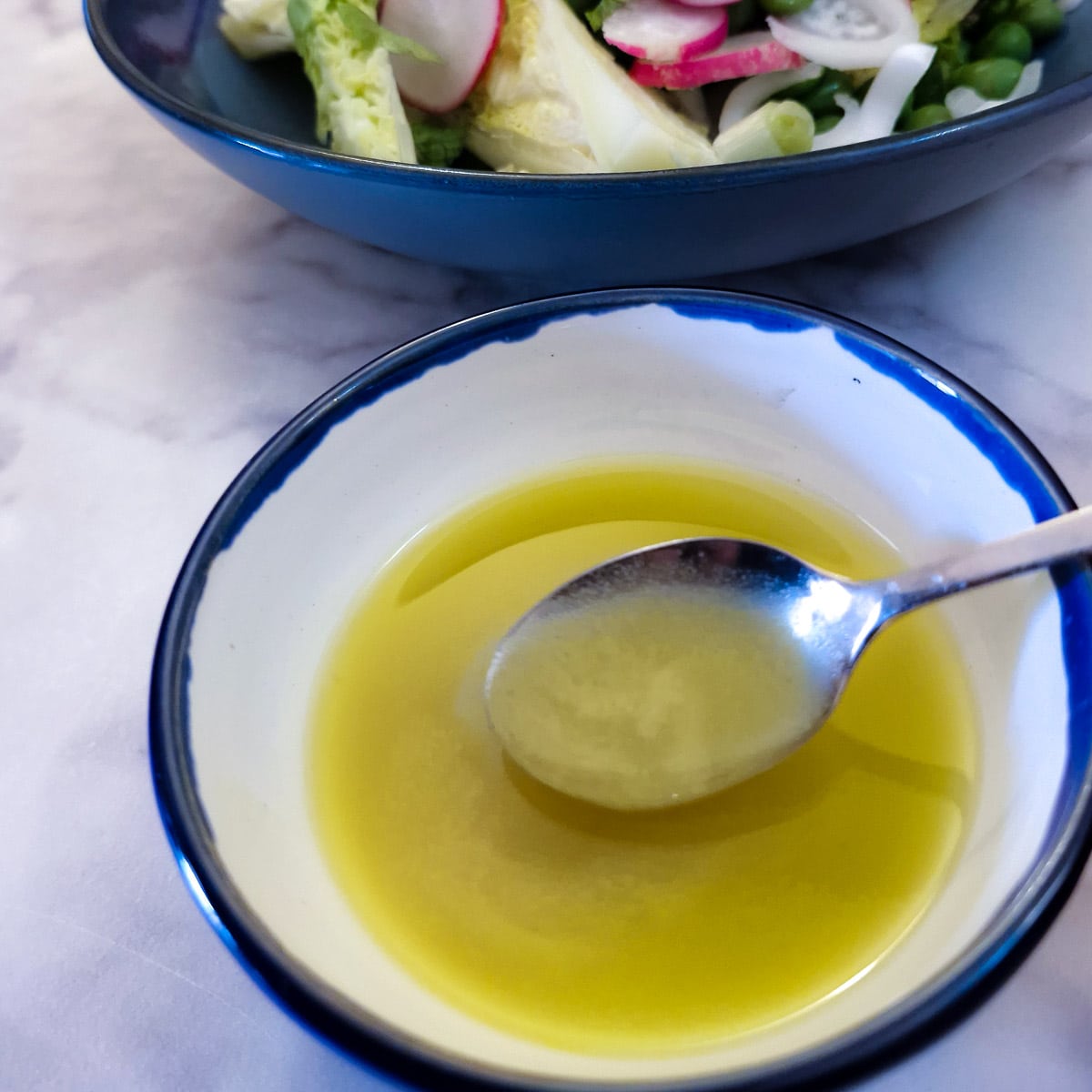 A small dish of salad dressing with a spoon.