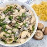A white serving dish filled with creamy mushroom pasta salad.