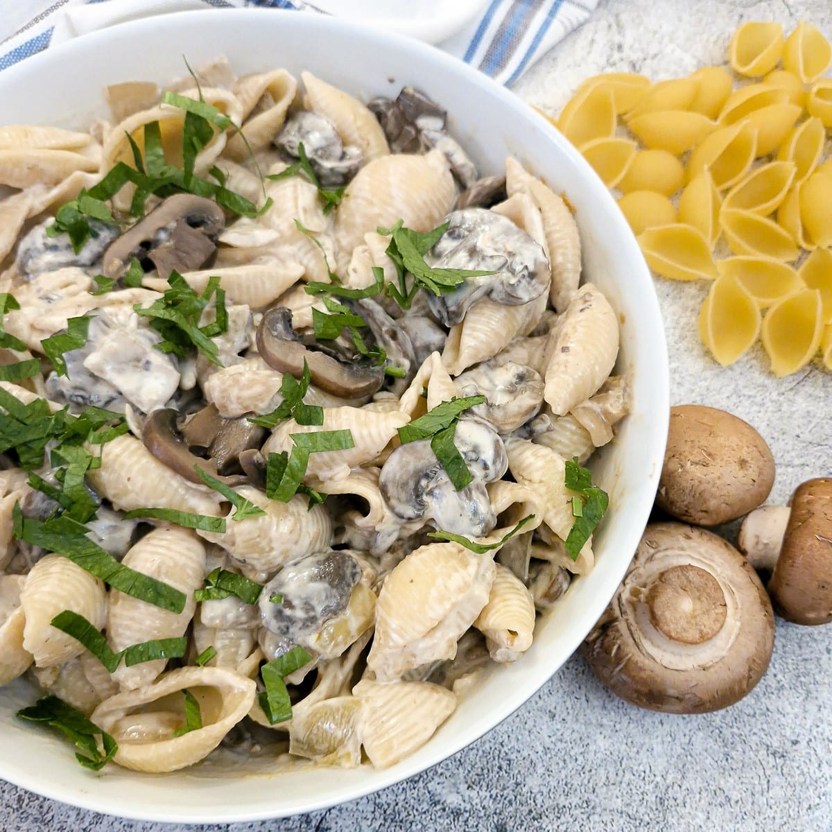A white serving dish filled with creamy mushroom pasta salad.