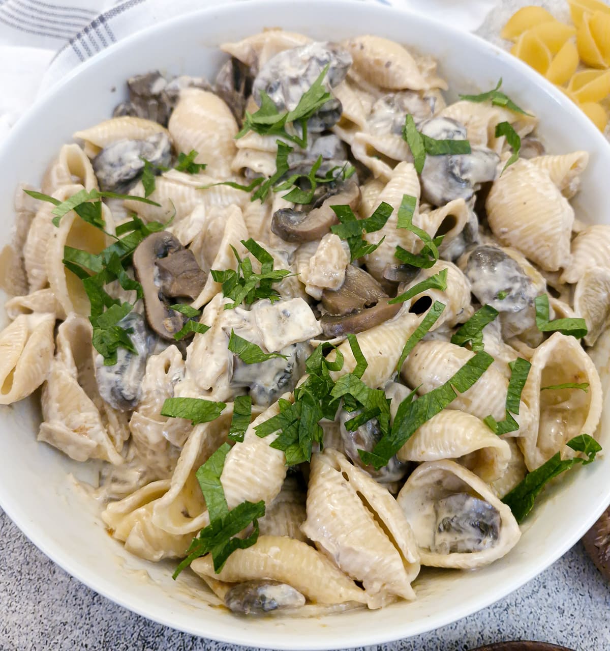 Mushroom pasta salad in a serving dish garnished with chopped parsley.