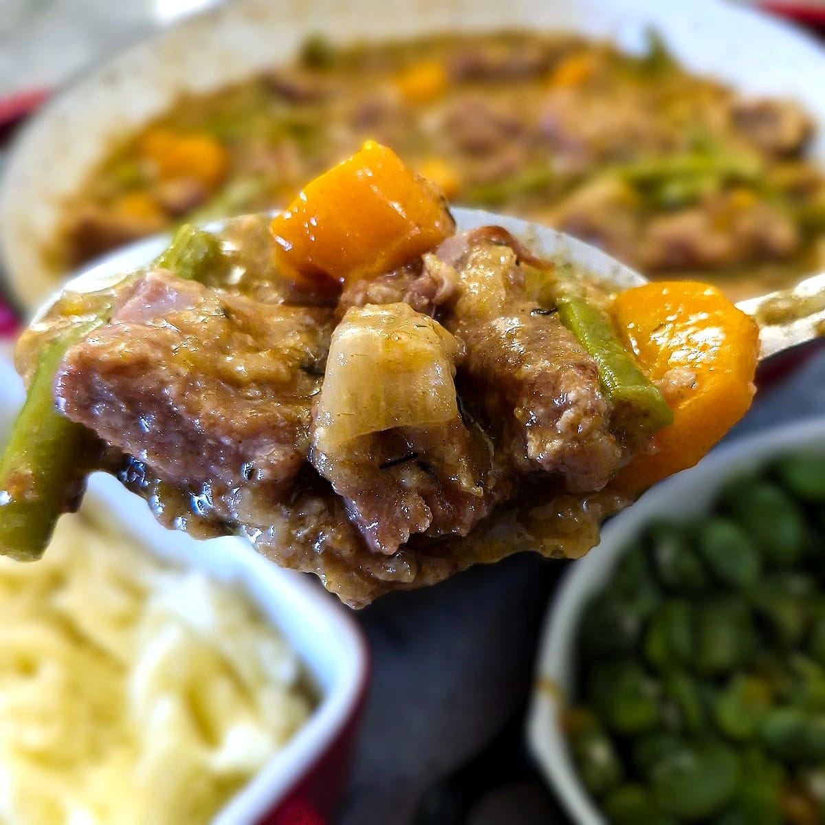 Close up of a serving spoon full of pork and apple casserole.