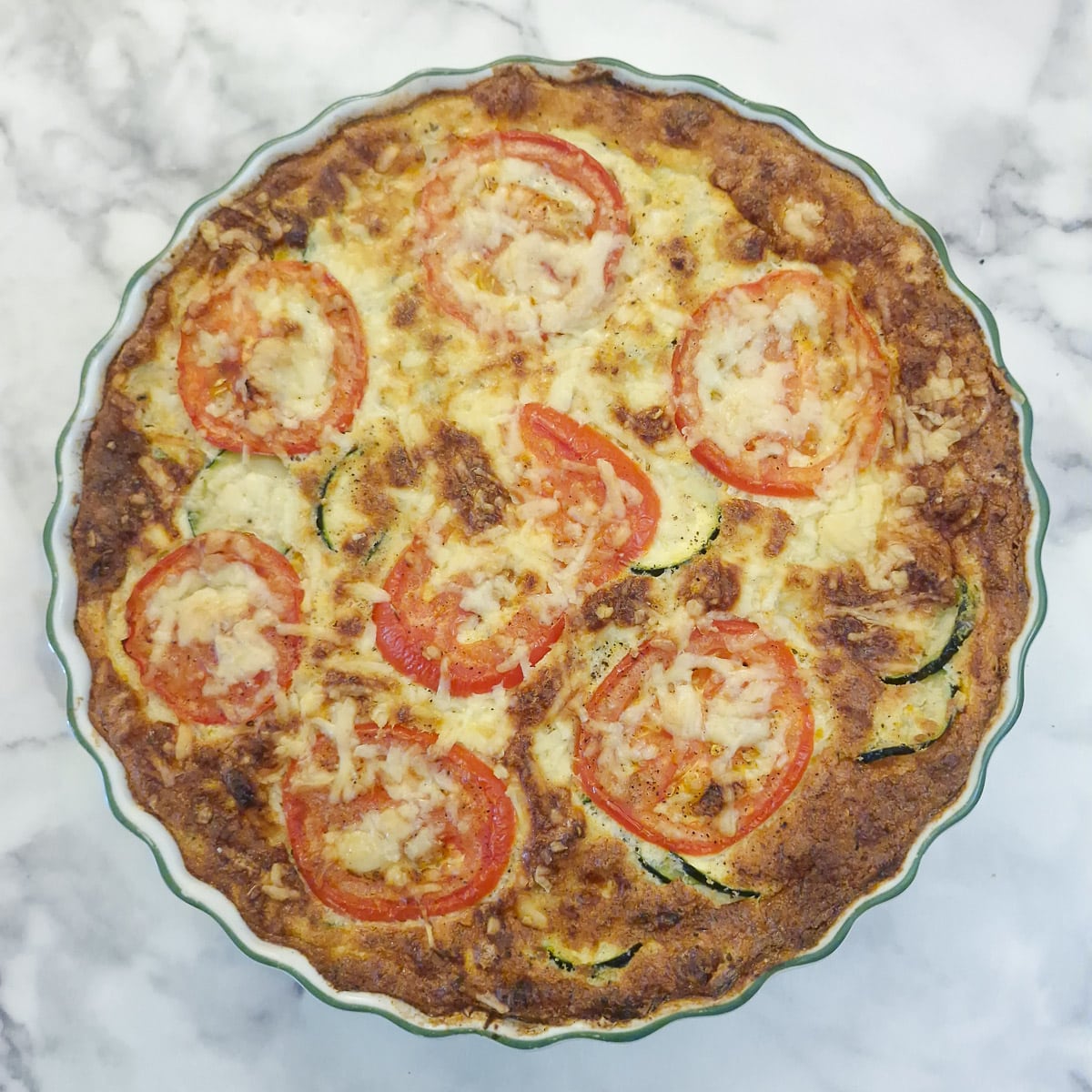 A baked courgette and carrot quiche in a round baking dish.