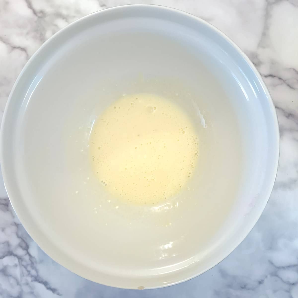 Egg yolks combined with cream cheese in a large mixing bowl.