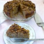A slice of easy apple and chestnut cake on a plate, showing the walnut and cinnamon sugar topping.