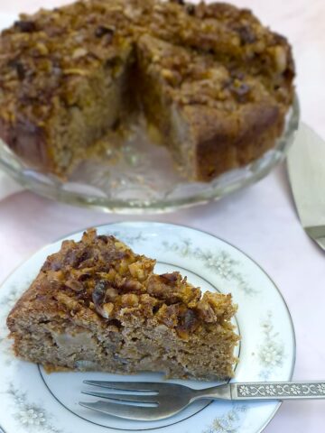 A slice of easy apple and chestnut cake on a plate, showing the walnut and cinnamon sugar topping.