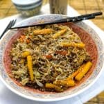 A serving dish filled with easy beef chow mein. There is a pair of chopsticks balanced on the dish.