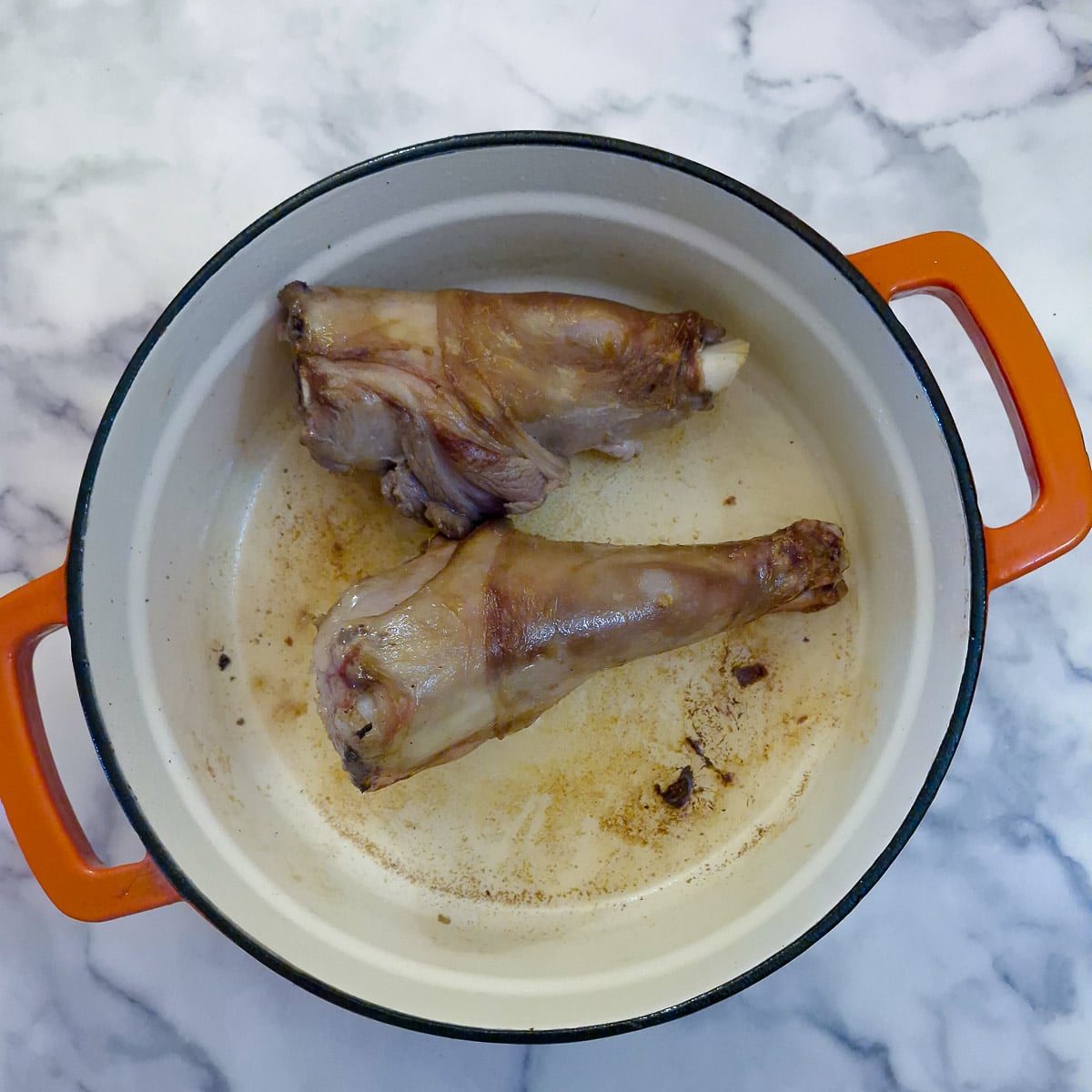 Step 1, 2 lamb shanks browning in a cast iron pot.