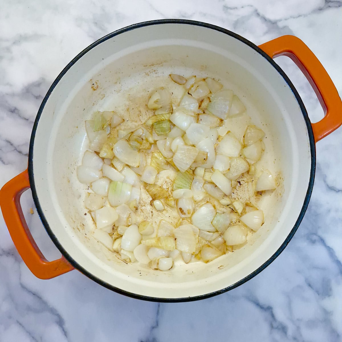 Step 2, onions being browned in a cast iron pot.