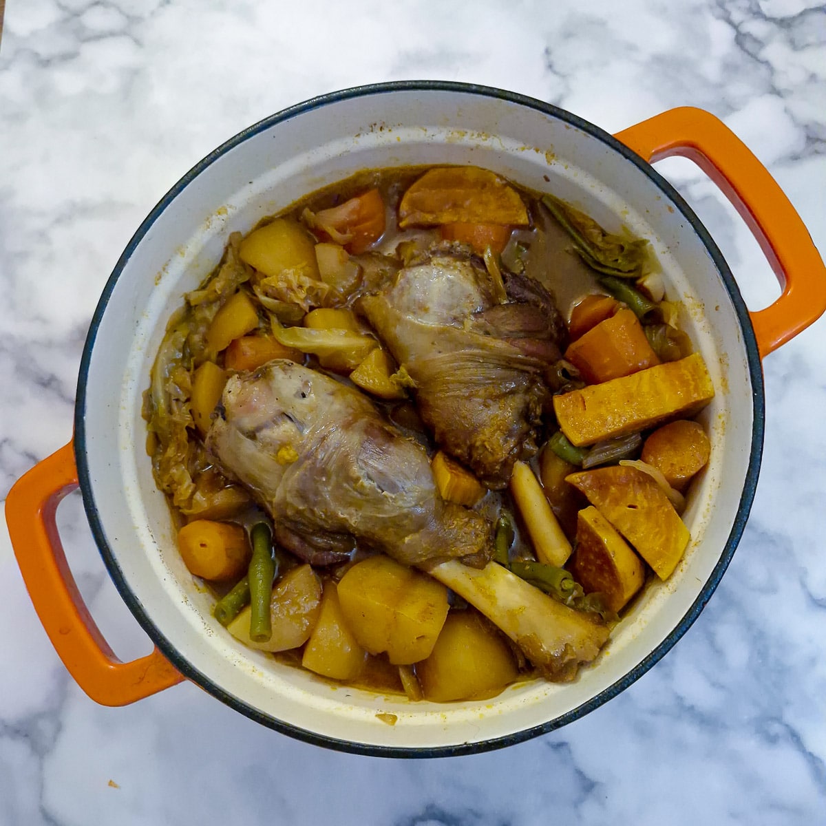 Step 6, cooked garlic lamb shanks and vegetables in a cast iron pan.