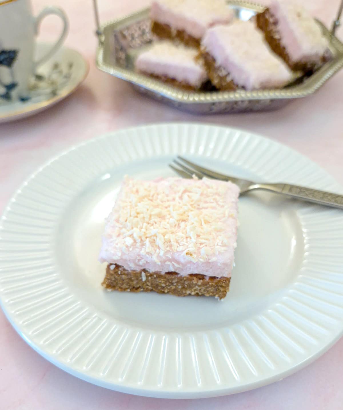 A sqiuare piece of coconut marshmallow wee-bix slice on a whte plate.