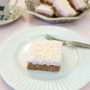 A sqiuare piece of coconut marshmallow wee-bix slice on a whte plate.