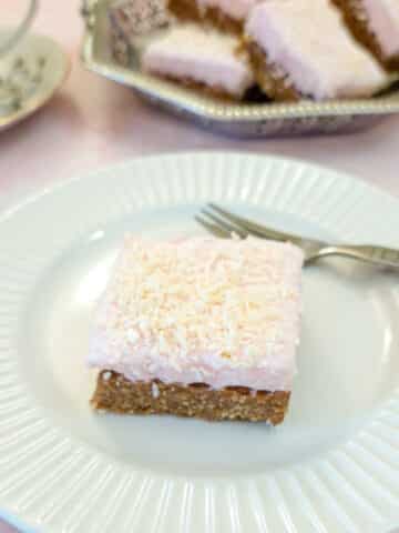 A sqiuare piece of coconut marshmallow wee-bix slice on a whte plate.