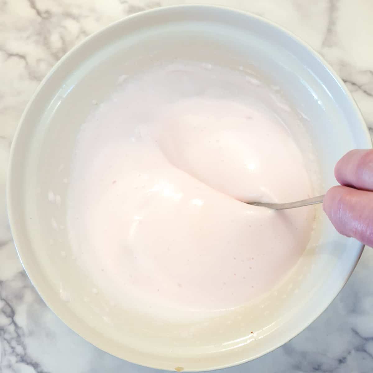 A large mixing bowl of thickened pink marshmallow mixture.