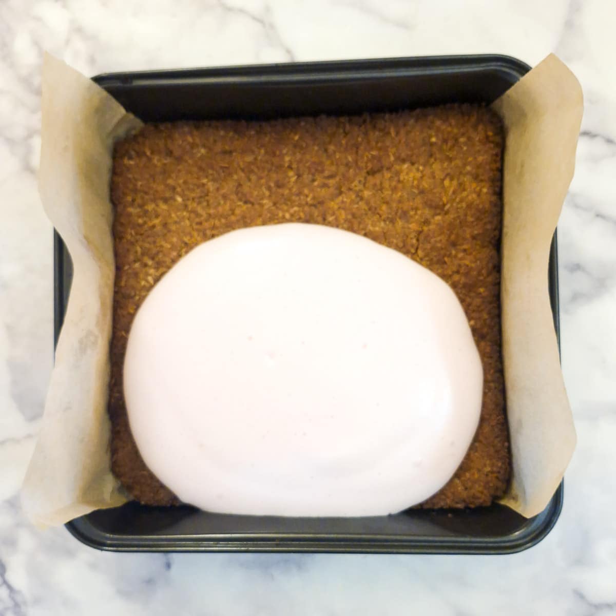 Marshmallow mixture being poured onto the baked biscuit base.