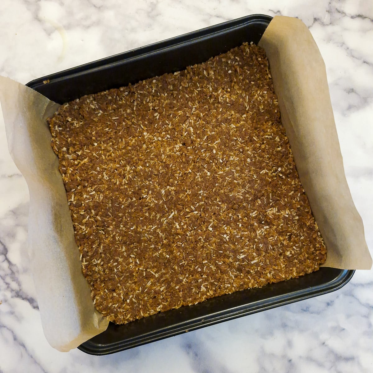 An unbaked biscuit base in a square lined baking dish.