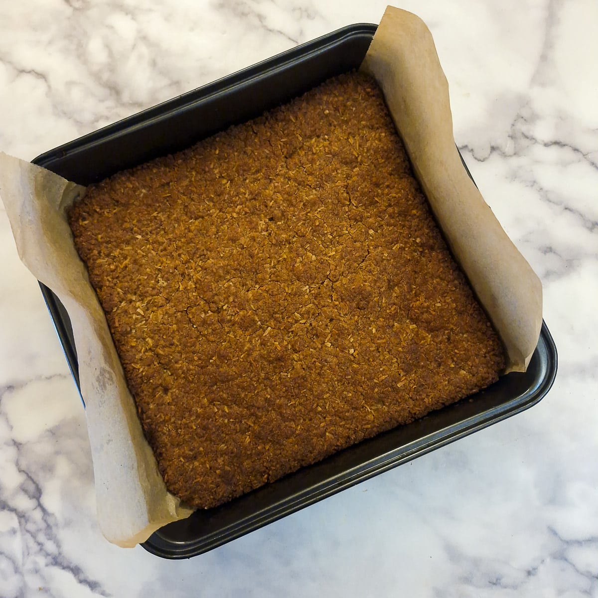 A fully baked biscuit base in a baking tin.