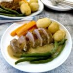 Duck a l'Orange on a dinner plate with vegetables and a helping of gravy.