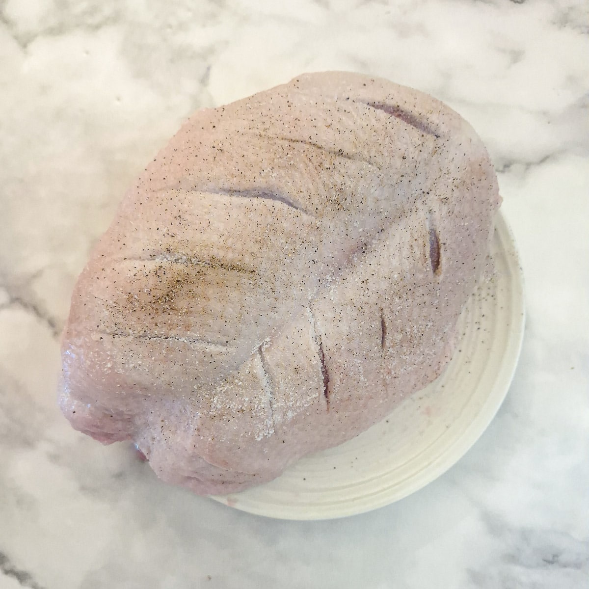 A duck crown that has been scored with a knife and rubbed with salt and pepper.