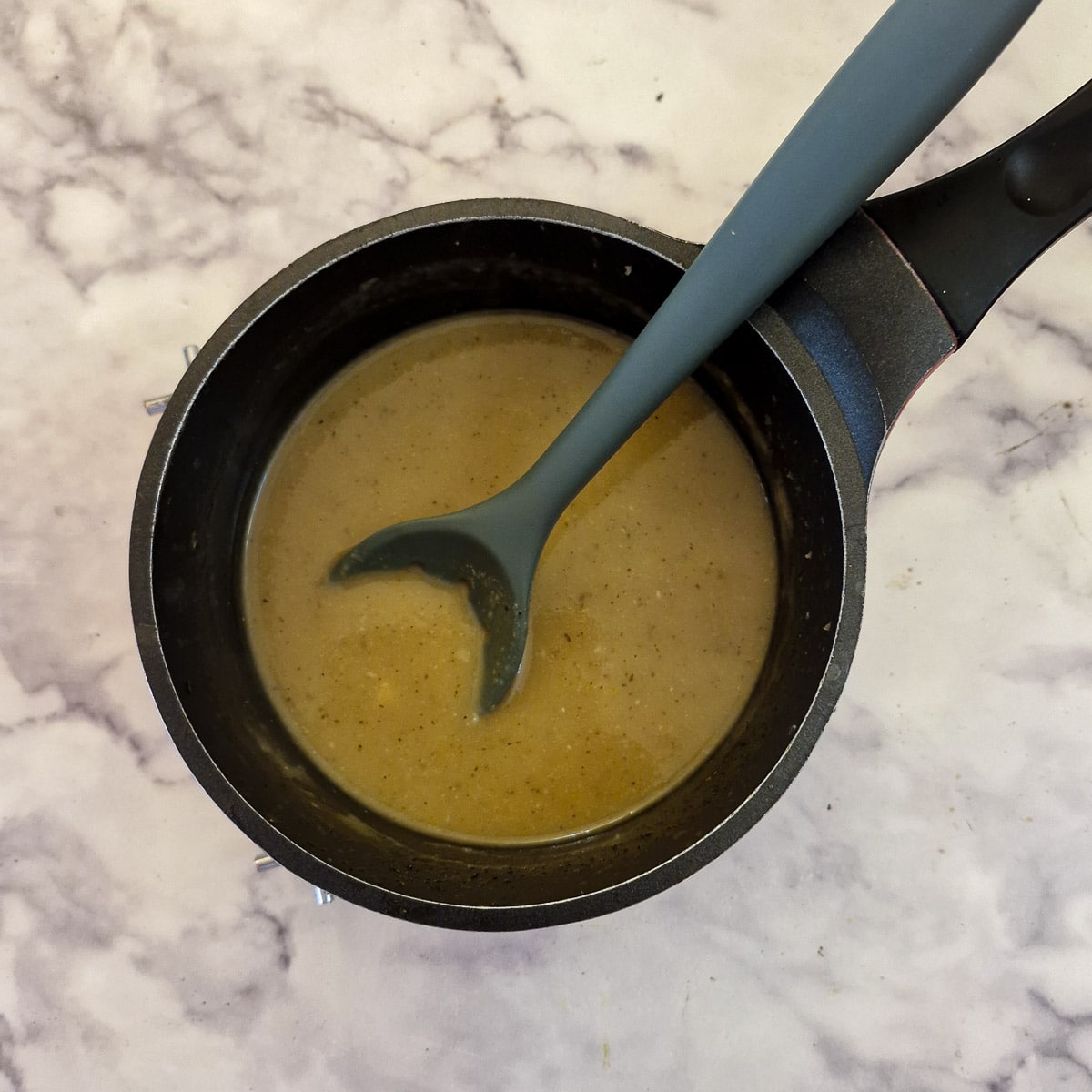 A saucepan of thickened orange sauce.