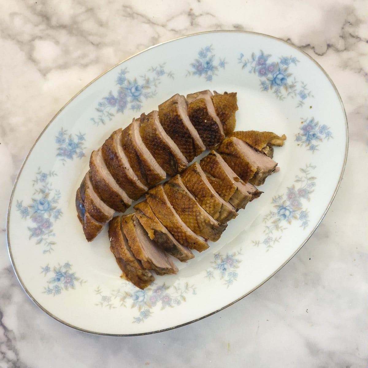 Sliced duck breasts arranged on a serving platter.