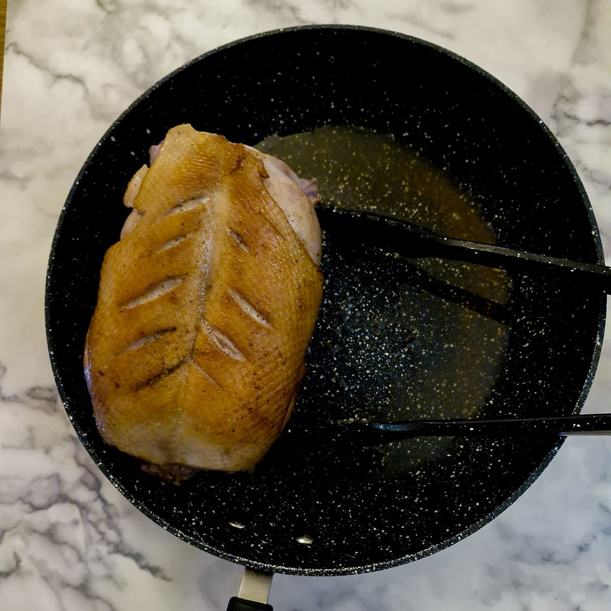 A duck crown browning in a frying pan.