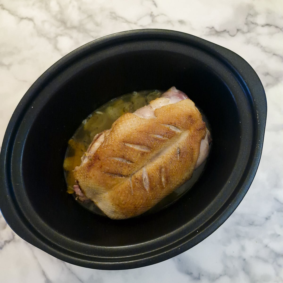 A browned duck crown added to the slow cooker.