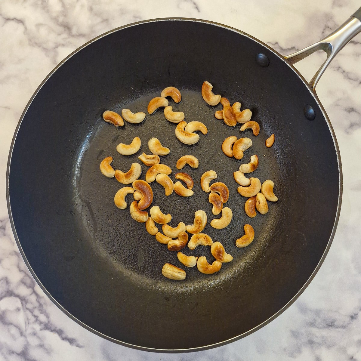 Step 1 cashew nuts browning in a frying pan.