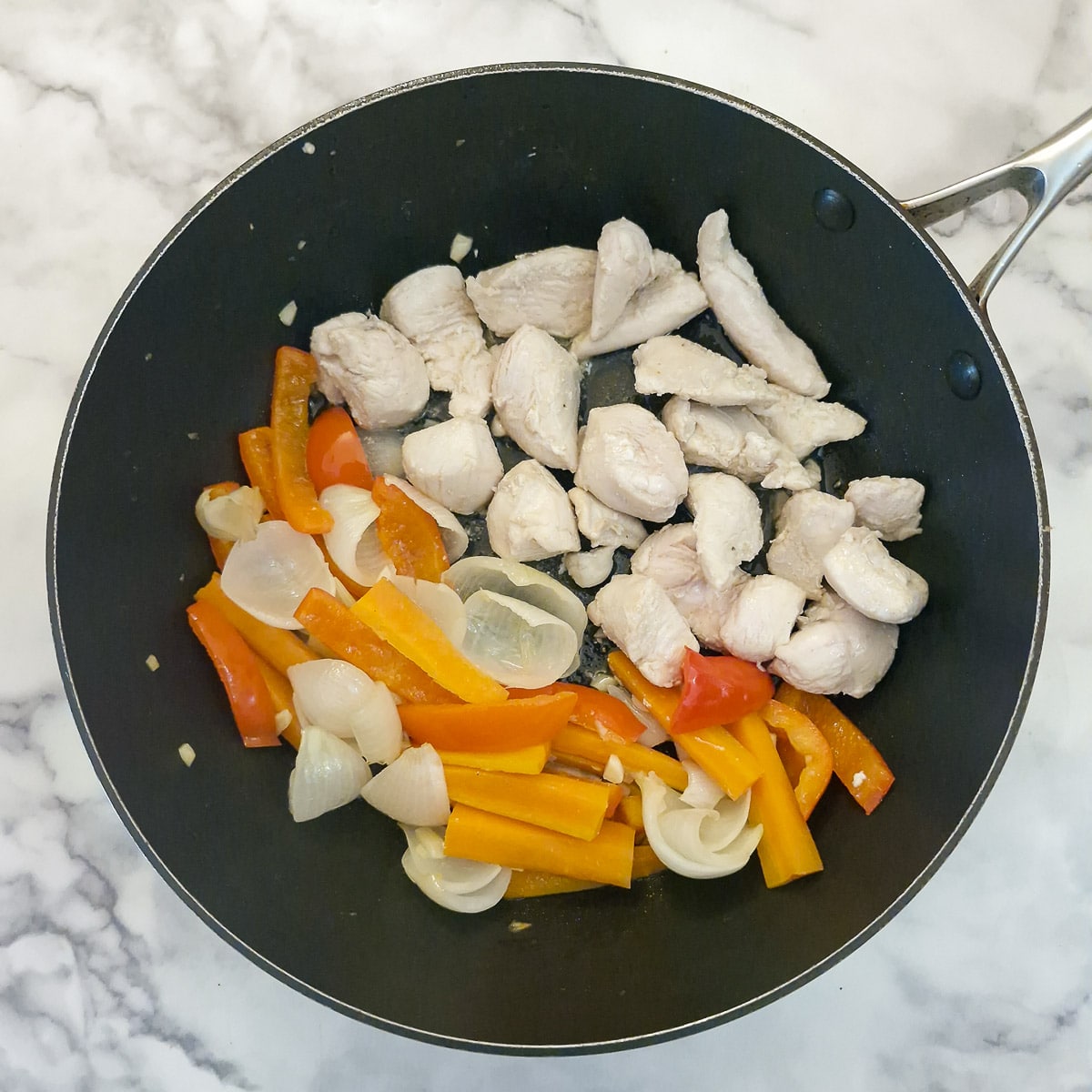 Step 3, pieces of chicken searing in a frying pan next to the carrots and onions.