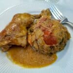 Chicken paprikash on a white plate with rice smothered in gravy.