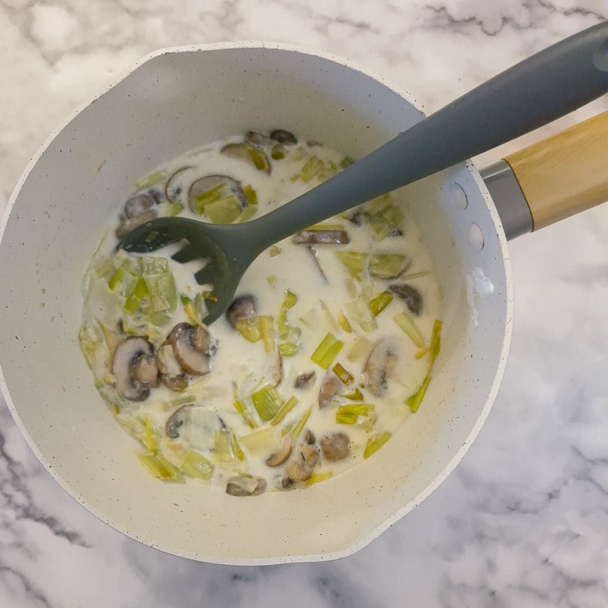 Milk and cornflour thickening in a saucepan with the leeks and mushrooms.