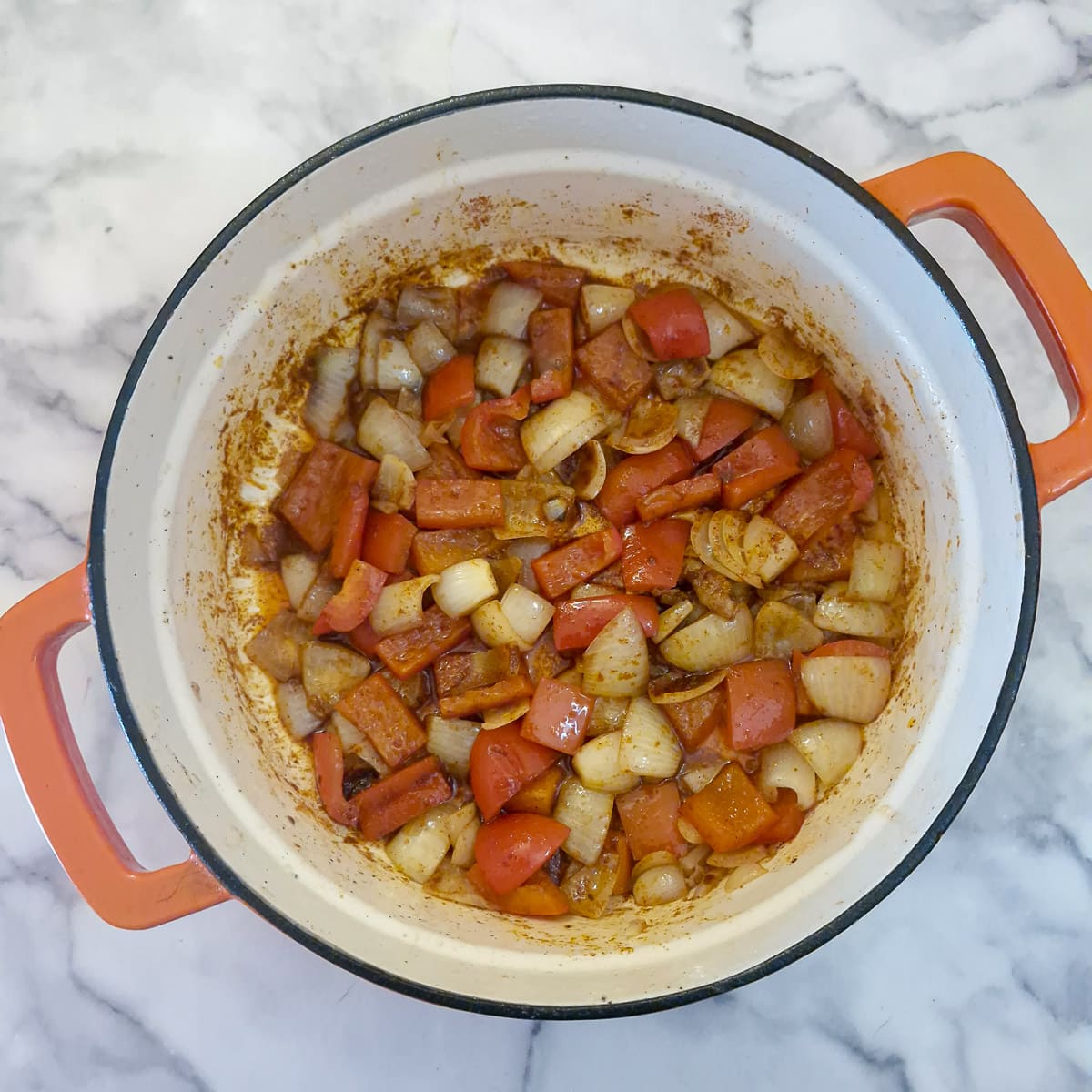 Paprika stirred into the pan to coat the onions and bell peppers.