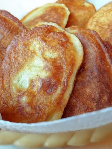 Fried scalloped potatoes in a bowl lined with kitchen paper.
