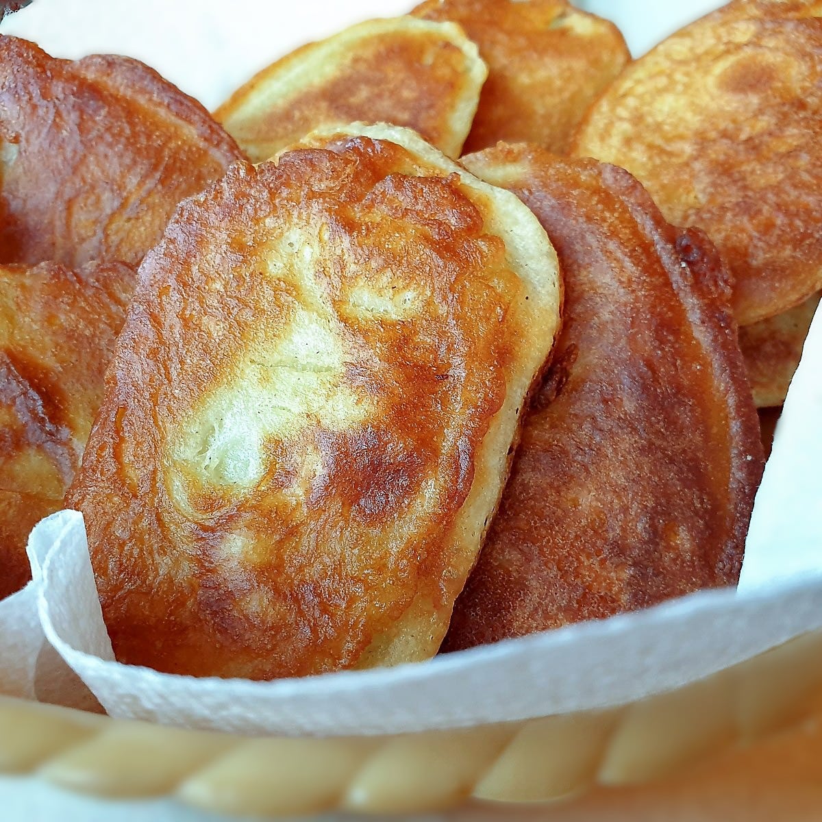 Fried scalloped potatoes in a bowl lined with kitchen paper.