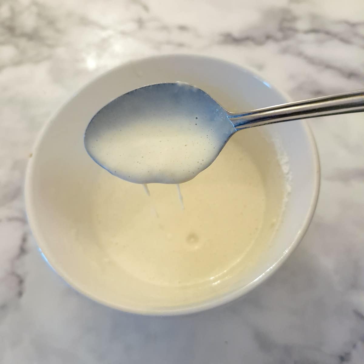 Batter being lifted from a bowl with a spoon.