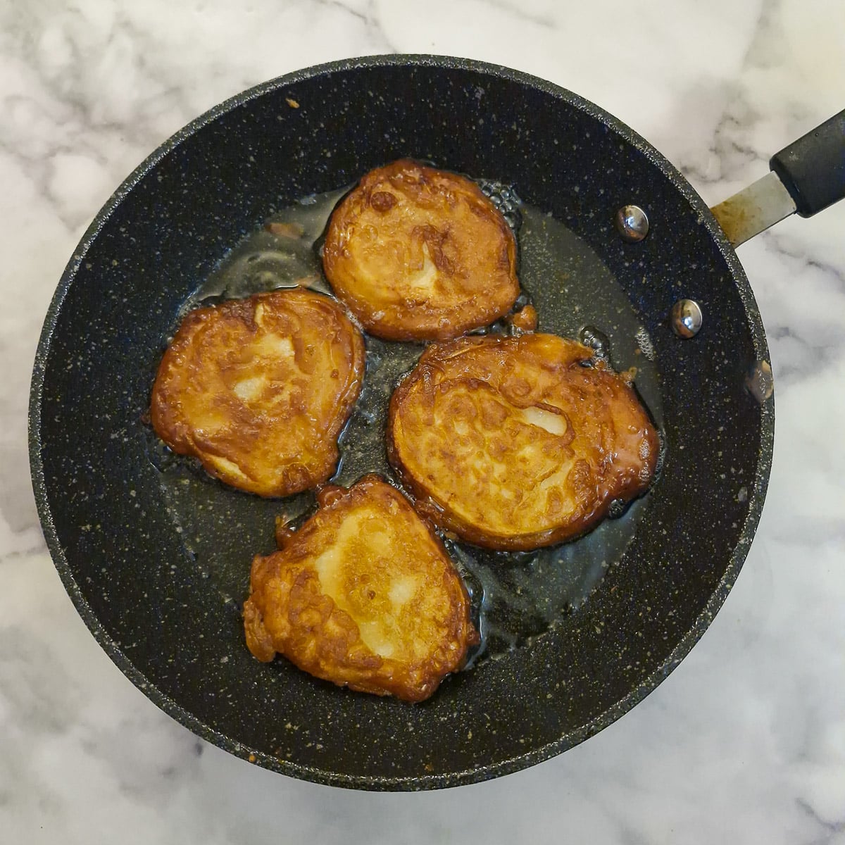 4 potato scaollops tuned over in a frying pan to brown the other side.