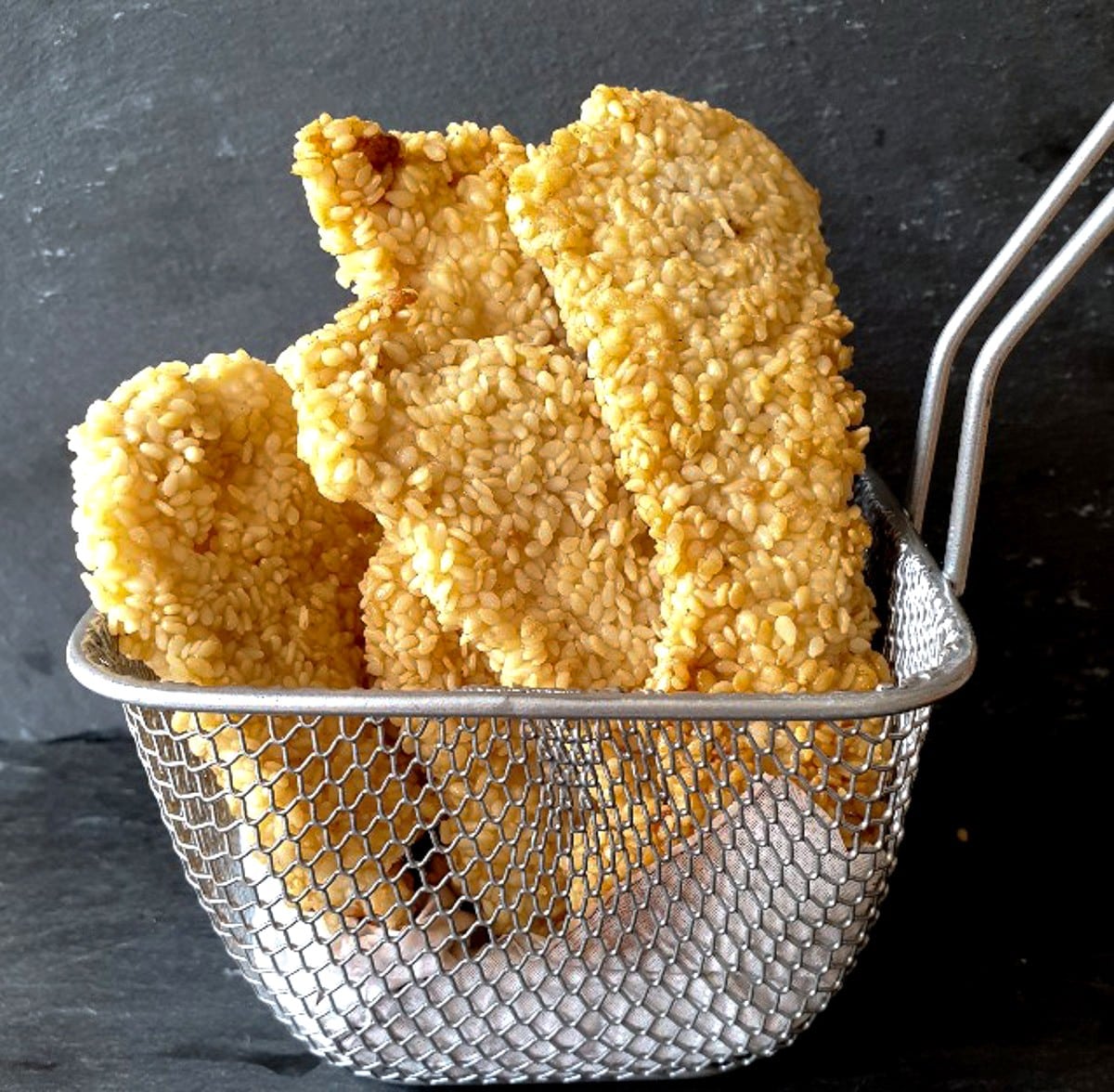 Sesame chicken strips in a wire small basket.