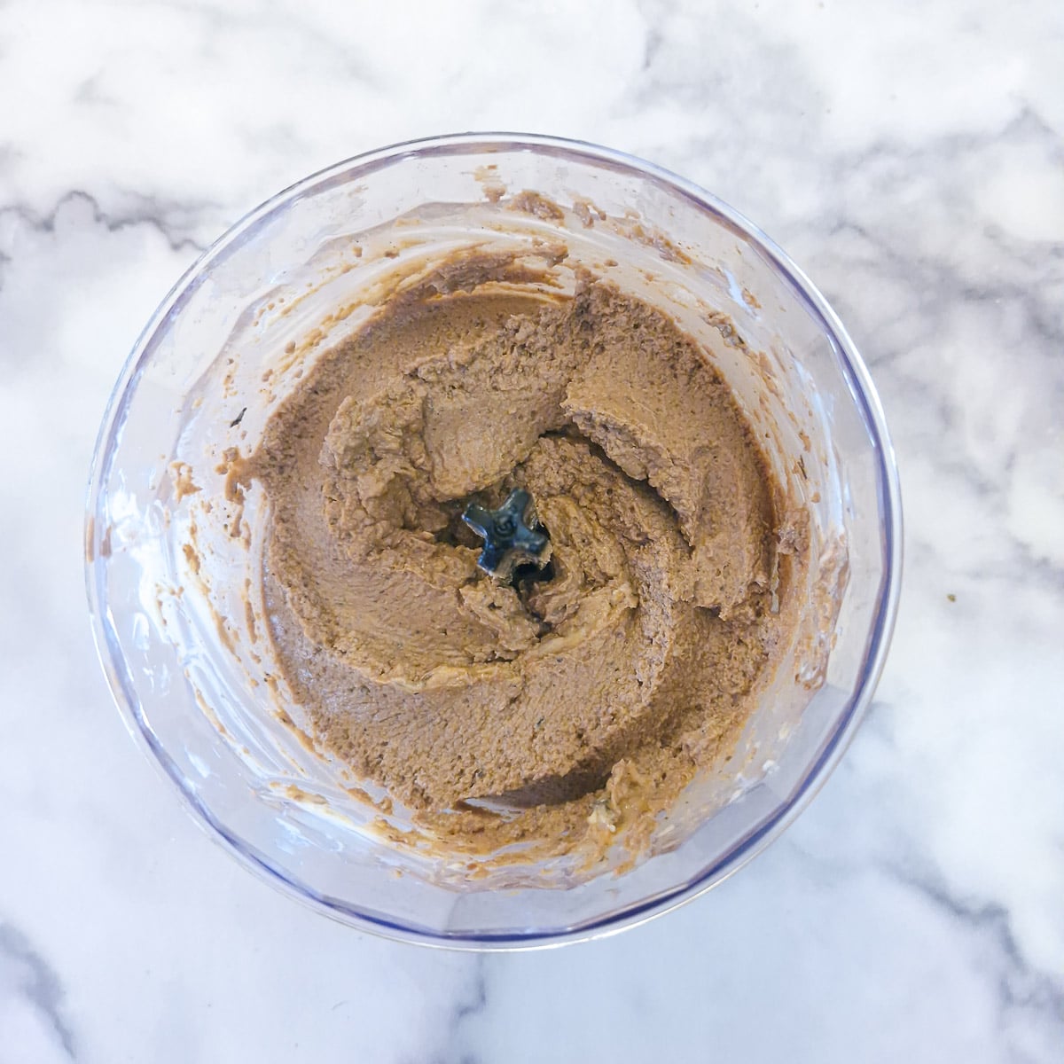 A food processer containing duck livers that have been blended with ceam and butter.