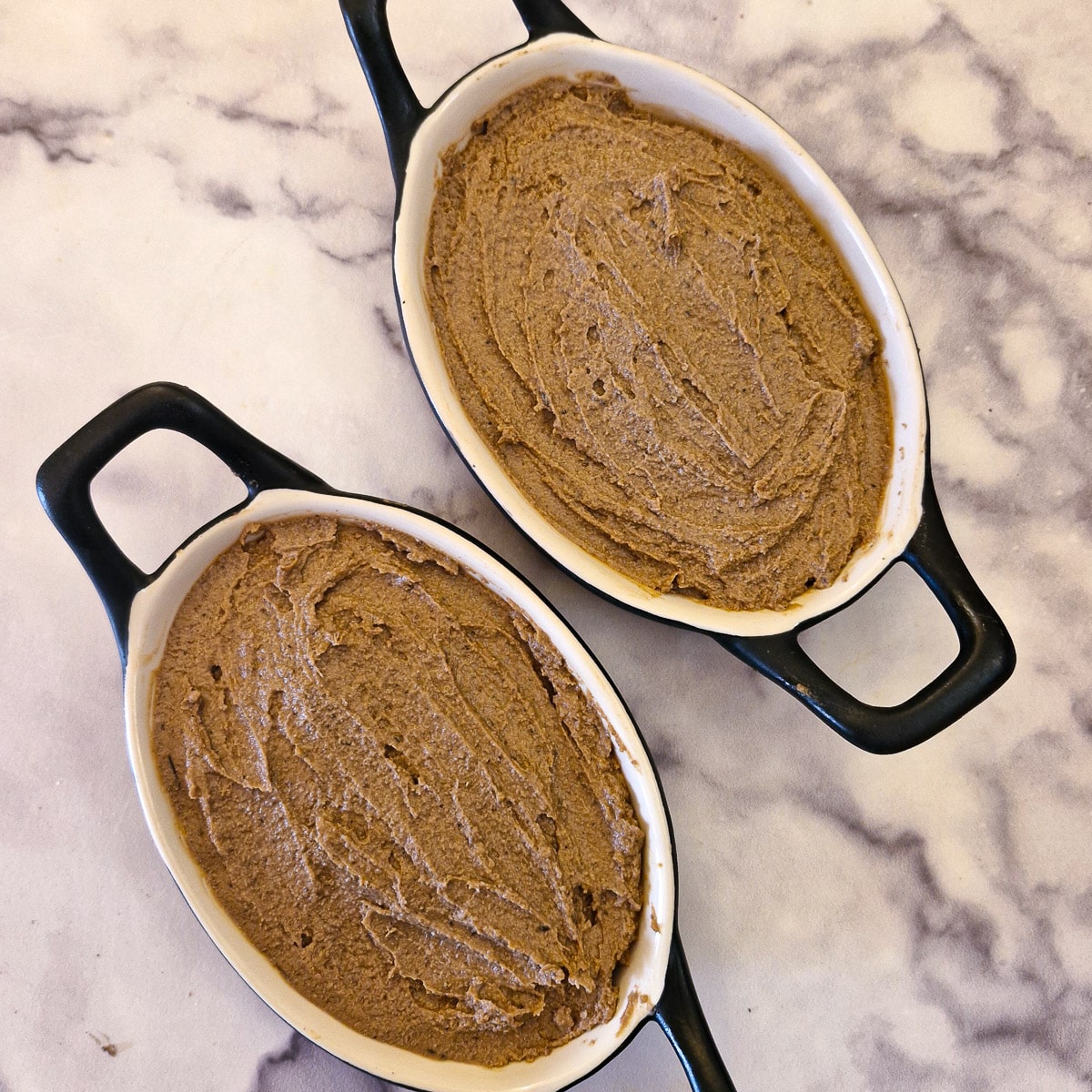 Two small black oval dishes filled with duck liver pate.