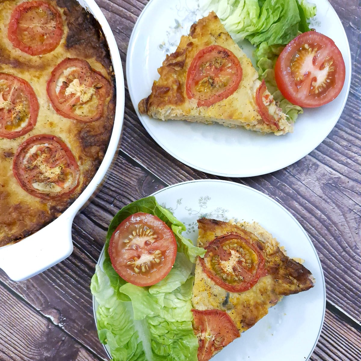 Slices of mortadella quiche on 2 plates with lettuce and tomato on the side.