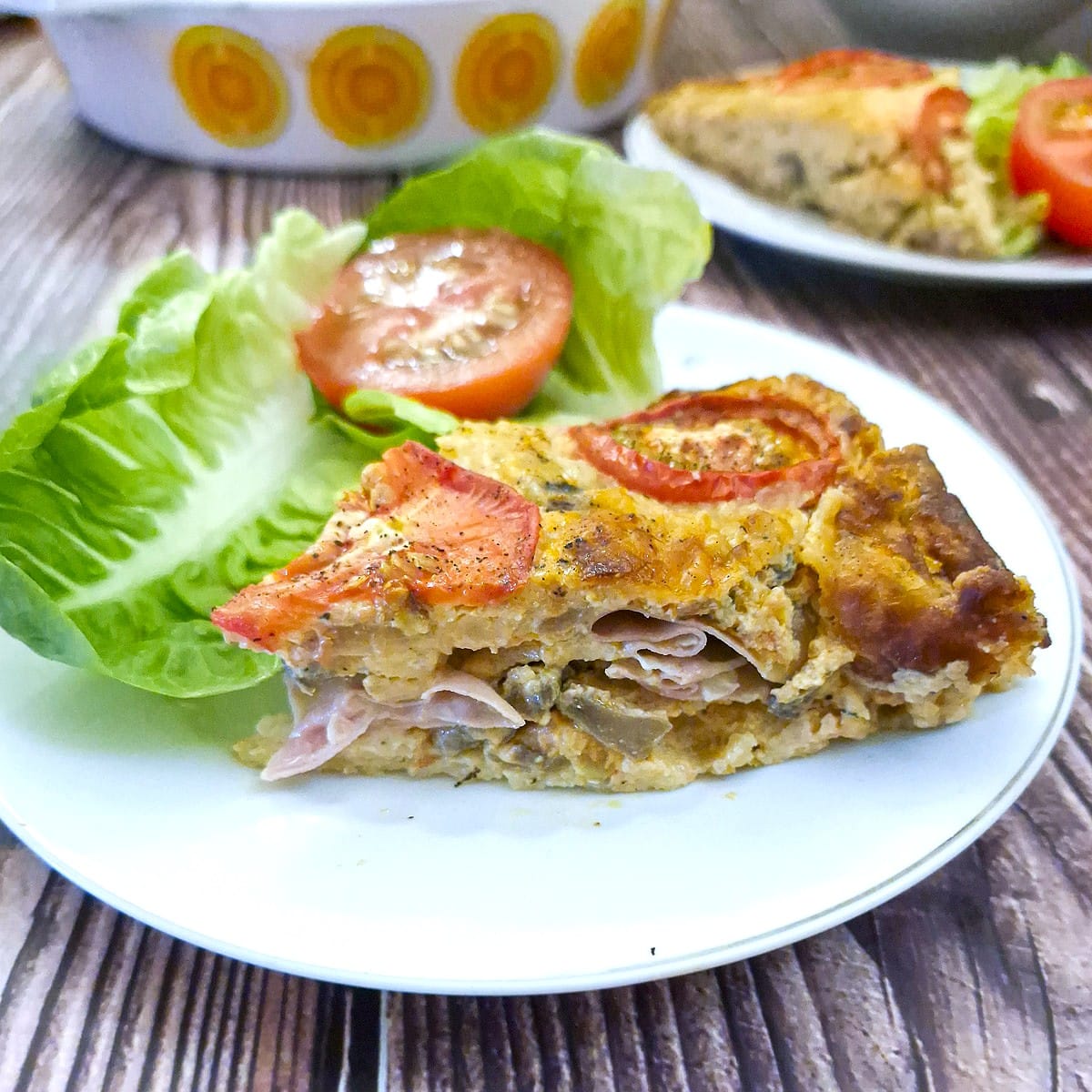 A slice of mortadella quiche on a white plate. Side-on view showing the inside.