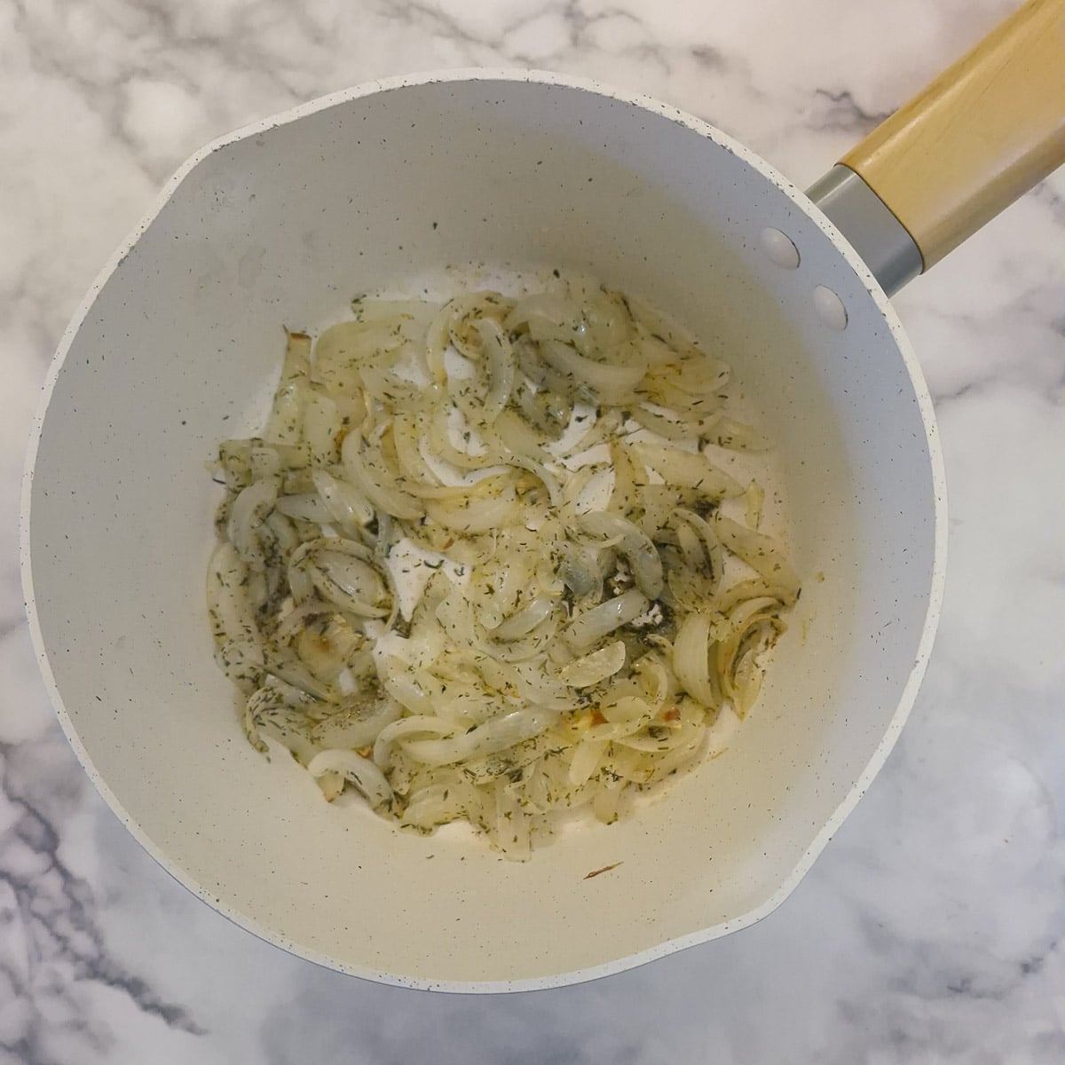 Sliced onions and thyme in a saucepan.