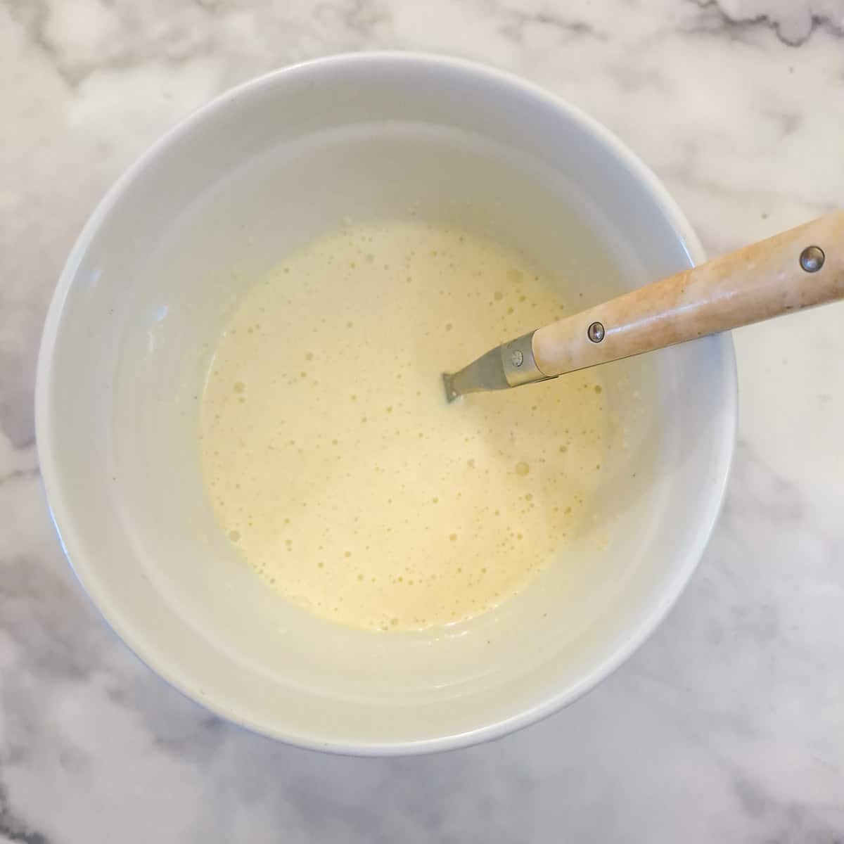 Eggs, cream, breadcrumbs and cheese mixed together in a small mixing bowl.