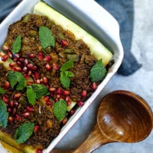 A dish of lamb keema stuffed marrows garnished with pomegranate seeds and mint leaves.