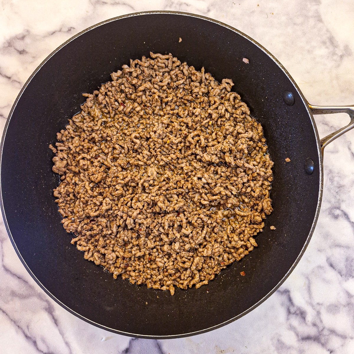 Lamb mince browning in a large pan.
