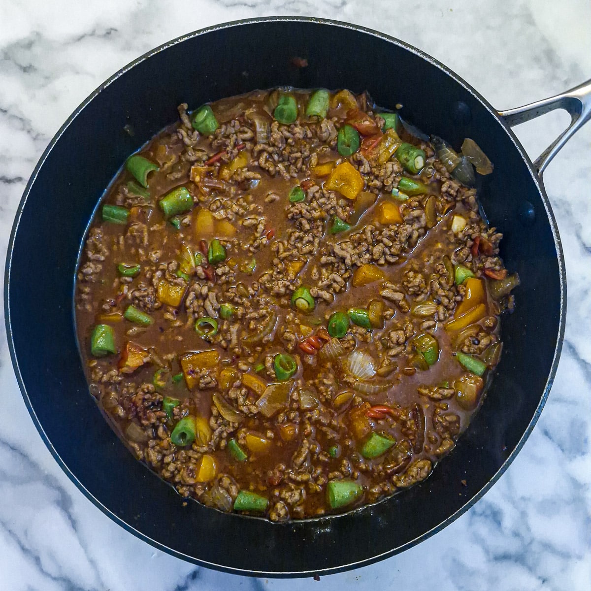 The browned mince added back to the pan along with stock and chopped green beans.