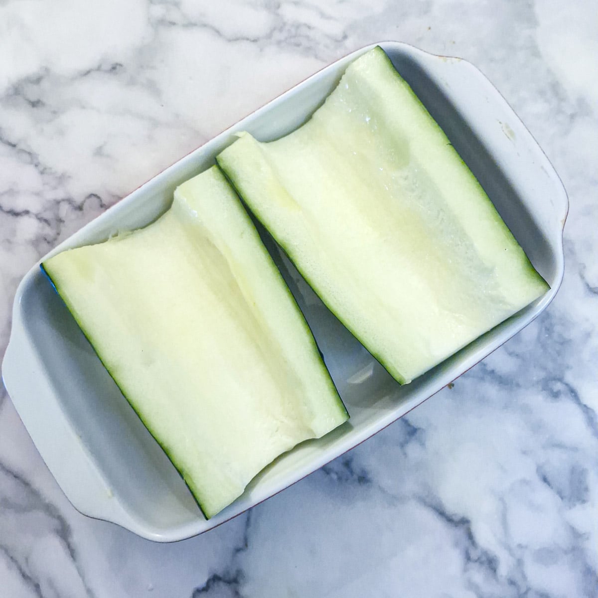 Two large pieces of hollowed-out marrow in a baking dish.